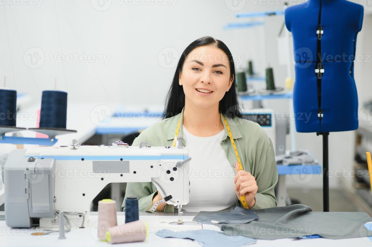 Portrait of a beautiful seamstress carrying a tape measure and working in a textile factory photo