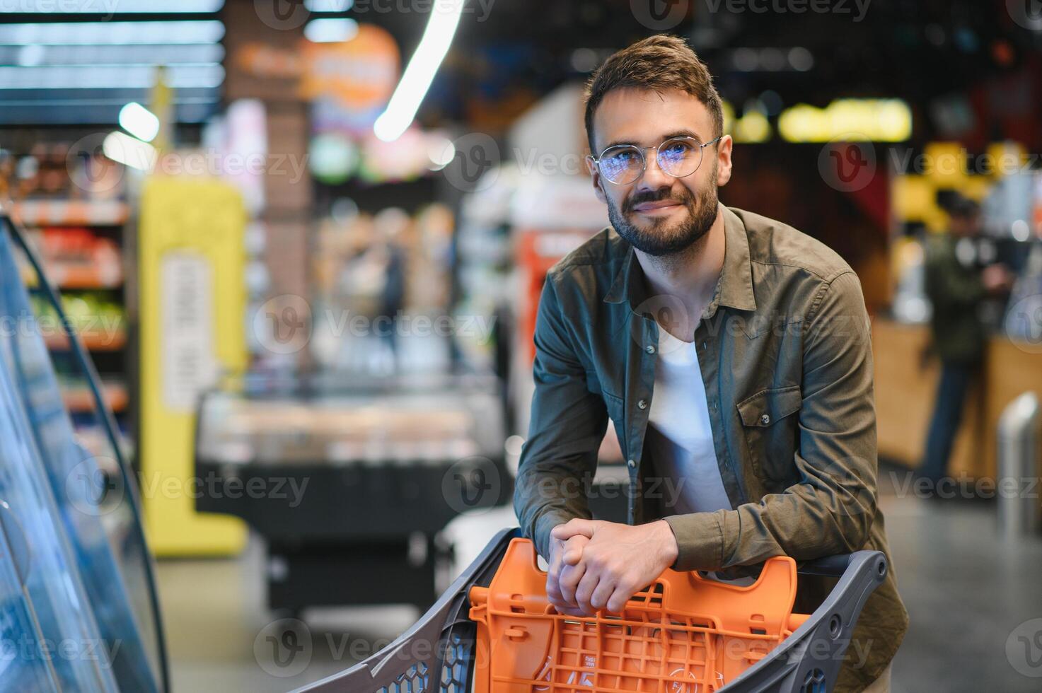 Portrait of smiling handsome man grocery shopping in supermarket, choosing food products from shelf photo