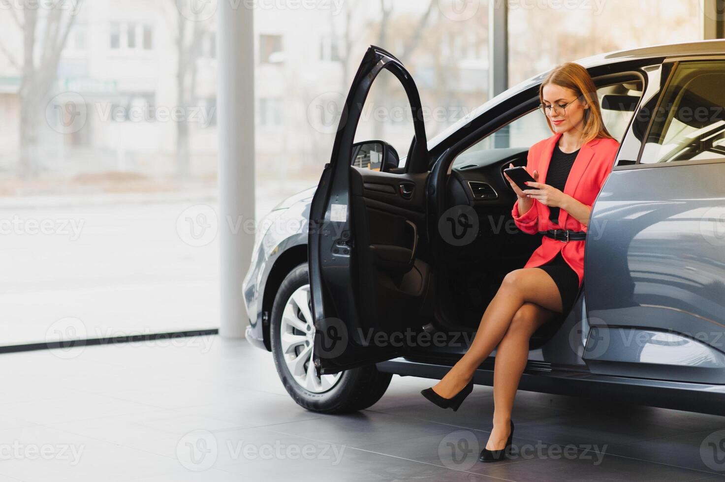 attractive businesswoman sitting in the car, talking on the phone and smiling photo