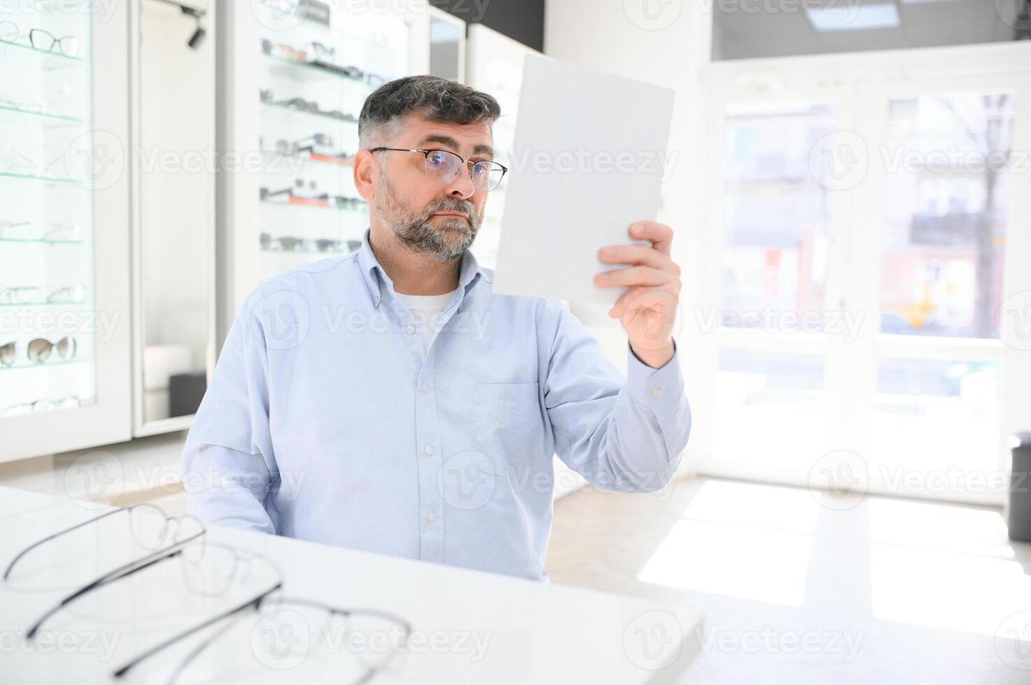 hermoso mayor hombre elegir los anteojos marco en óptico almacenar. foto