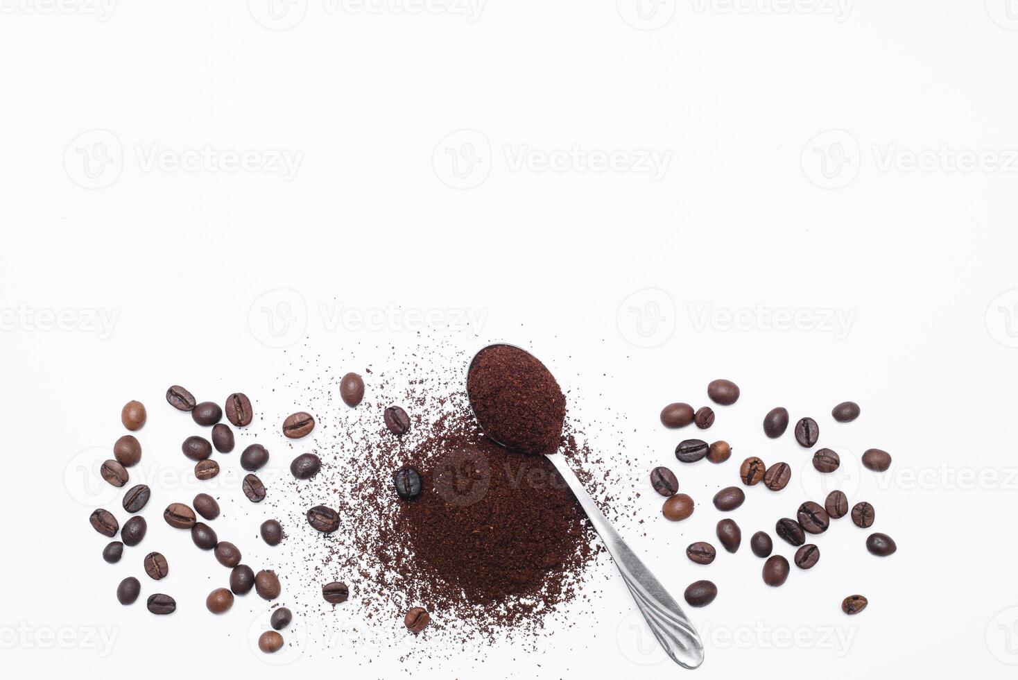 Grounded coffee in a spoon surrounded with beans isolated photo