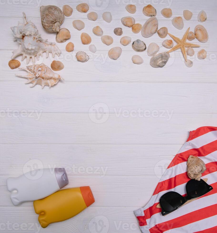 playa accesorios. toalla, chancletas, estrella de mar, barco y Gafas de sol en de madera antecedentes. parte superior ver con Copiar espacio. soleado tonificado foto