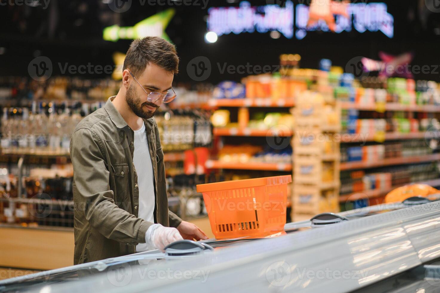 retrato de sonriente hermoso hombre tienda de comestibles compras en supermercado, elegir comida productos desde estante foto