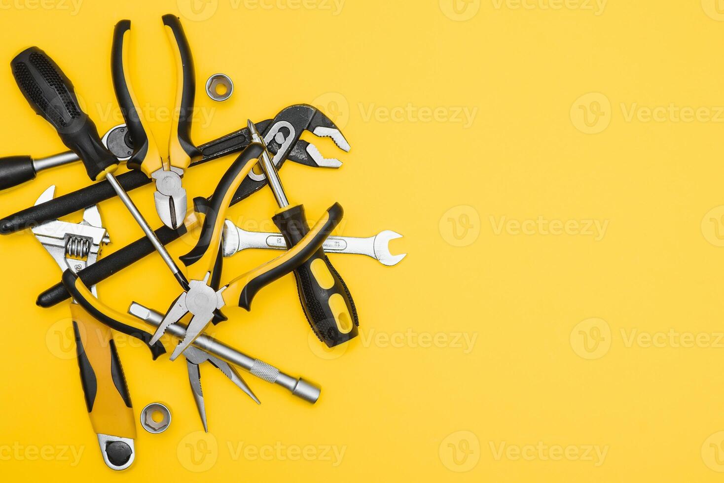 Yellow and black handy tools pilers and screwdriver isolated on yellow background. photo