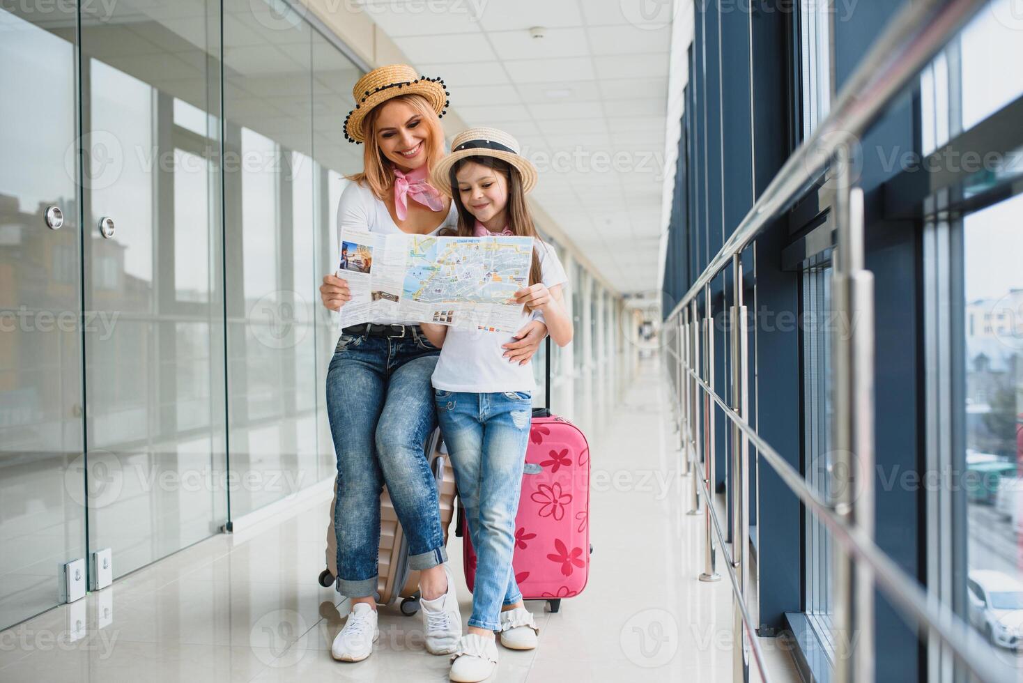 madre y pequeño hija con equipaje y mapa a aeropuerto terminal Listo para vacaciones. foto