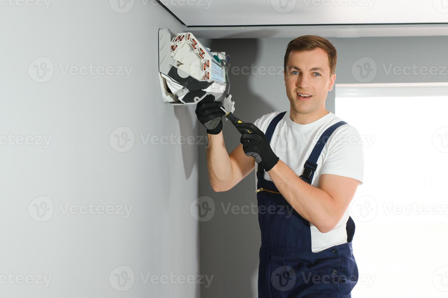 handsome young man electrician installing air conditioning in a client house photo