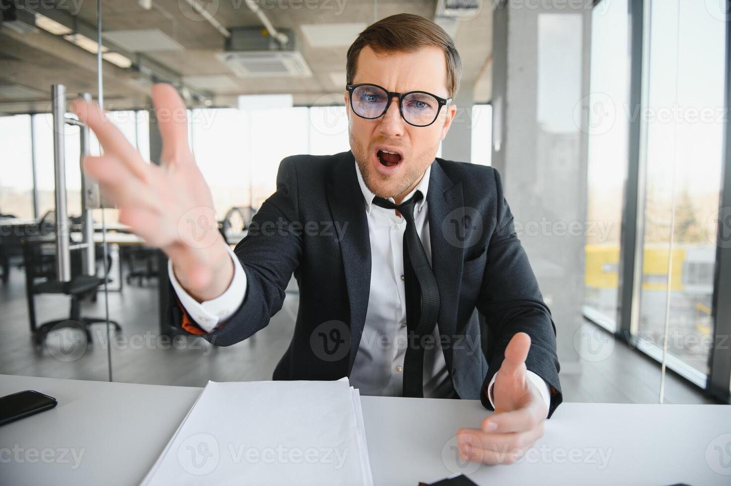 Angry businessman sitting at his desk and screaming at his employees. photo
