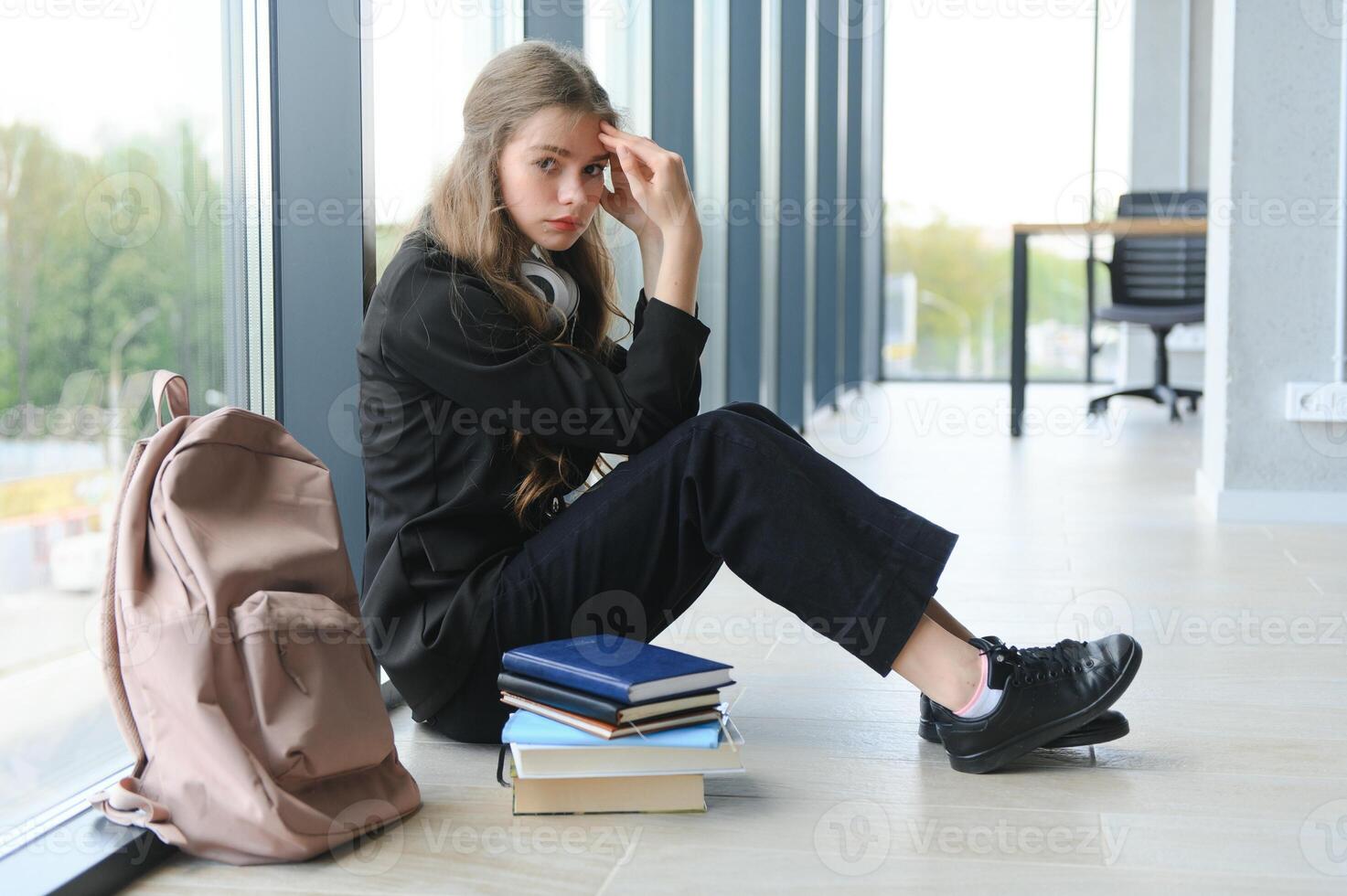 Upset teen girl sit on floor sadly look out window worried about teenage problem at school and communication with parent. Worried girl tensely suffer about bullying at school photo