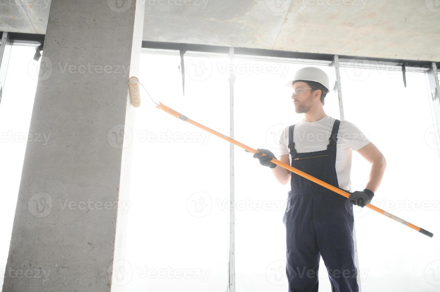 Painter man painting the wall, with paint roller. photo