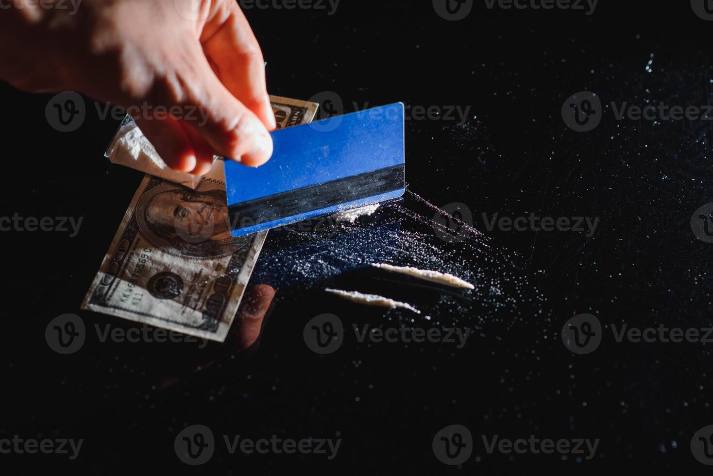 Close up of hands of young druggie is doing tracks of cocaine with a credit card. photo