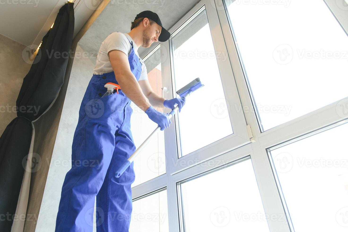 joven limpiando ventana en la oficina foto