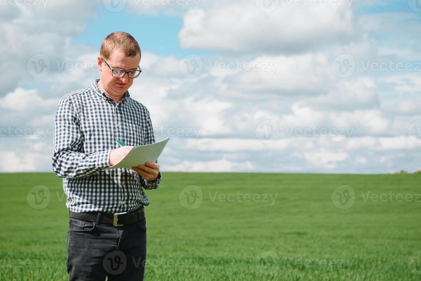 Young farmer on a wheat field. Young wheat in spring. Agriculture concept. An agronomist examines the process of ripening wheat in the field. The concept of the agricultural business. photo