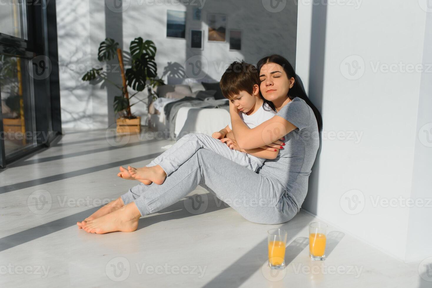 Young mother with her 4 years old little son dressed in pajamas are relaxing and playing in the bedroom at the weekend together, lazy morning. photo