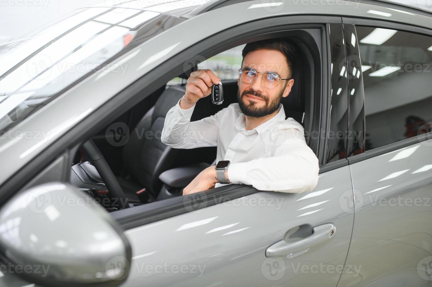 Yes, that's my new car. Customer in car dealership. Young man with keys in hand photo