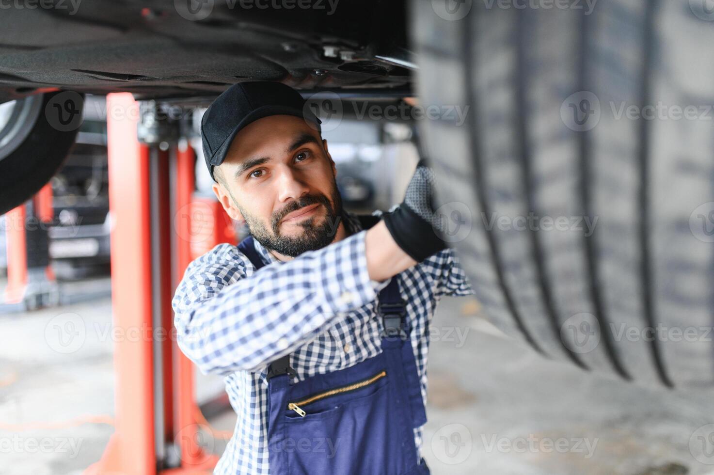 Auto mechanic working underneath a lifted car photo