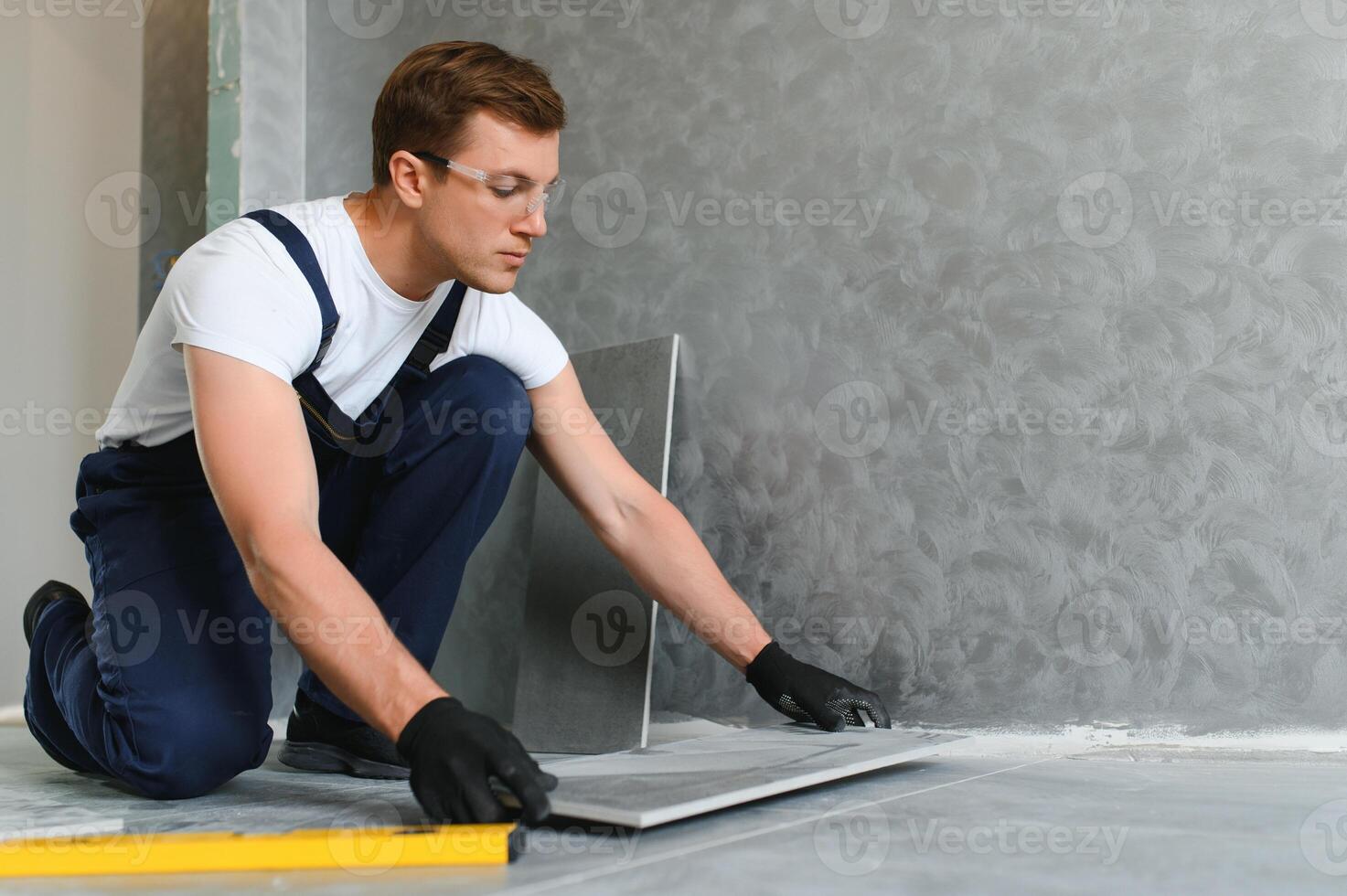 industrial worker, handyman installing big ceramic tiles photo