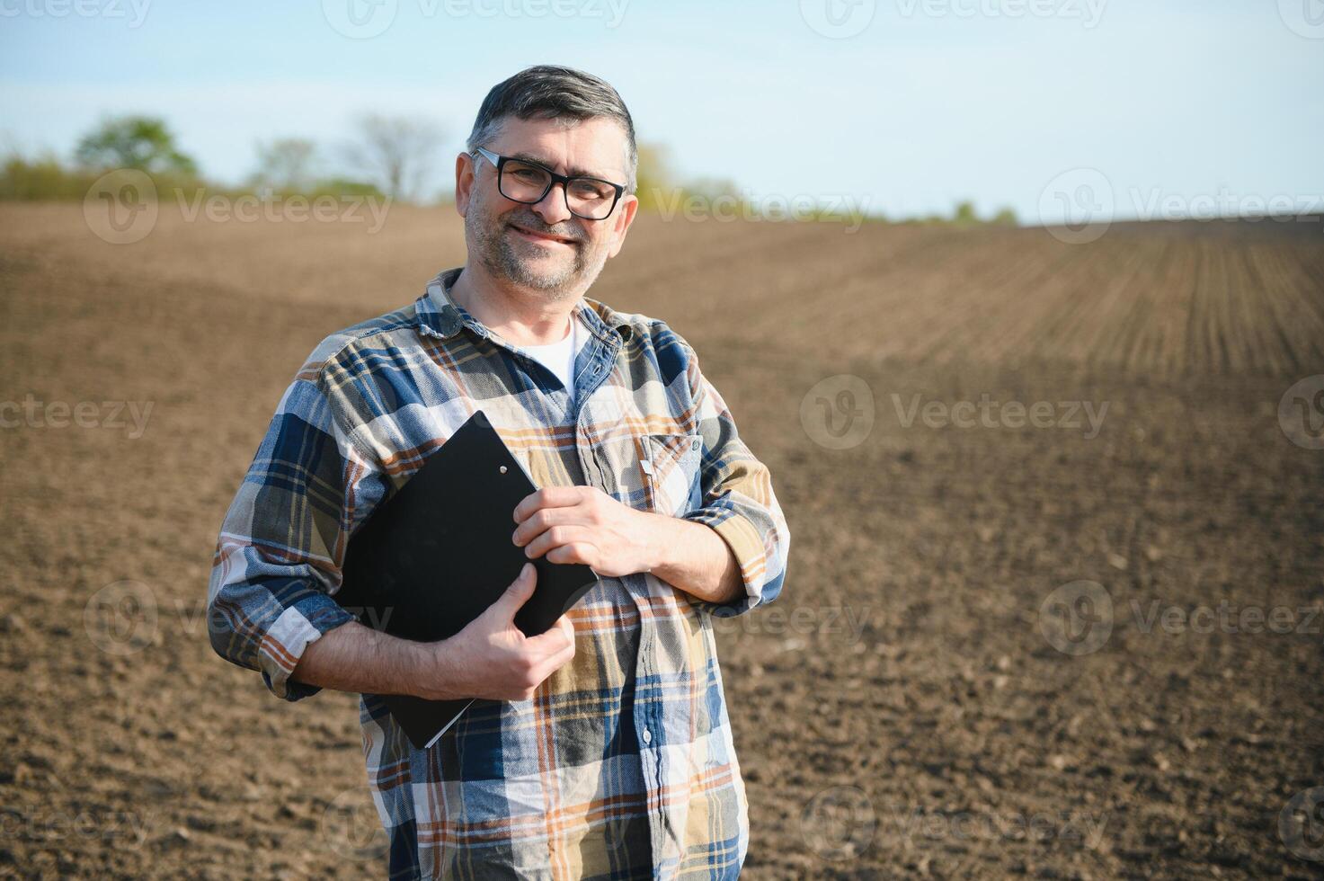 A farmer works in a field sown in spring. An agronomist walks the earth, assessing a plowed field in autumn. Agriculture. Smart farming technologies. photo