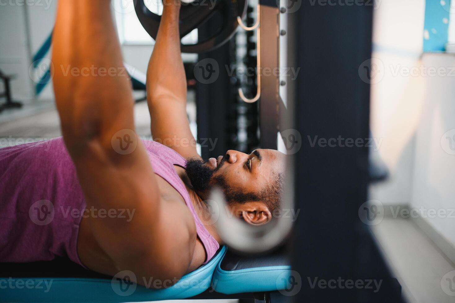 Weight lifter at the bench press lifting a barbell on an bench. photo