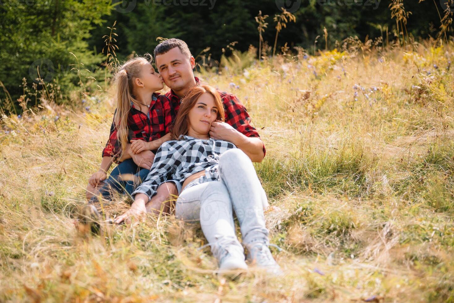 Family of three people rest in the mountains. They sat down to rest, drink water after a hard climb to the mountain. They are tired but happy photo