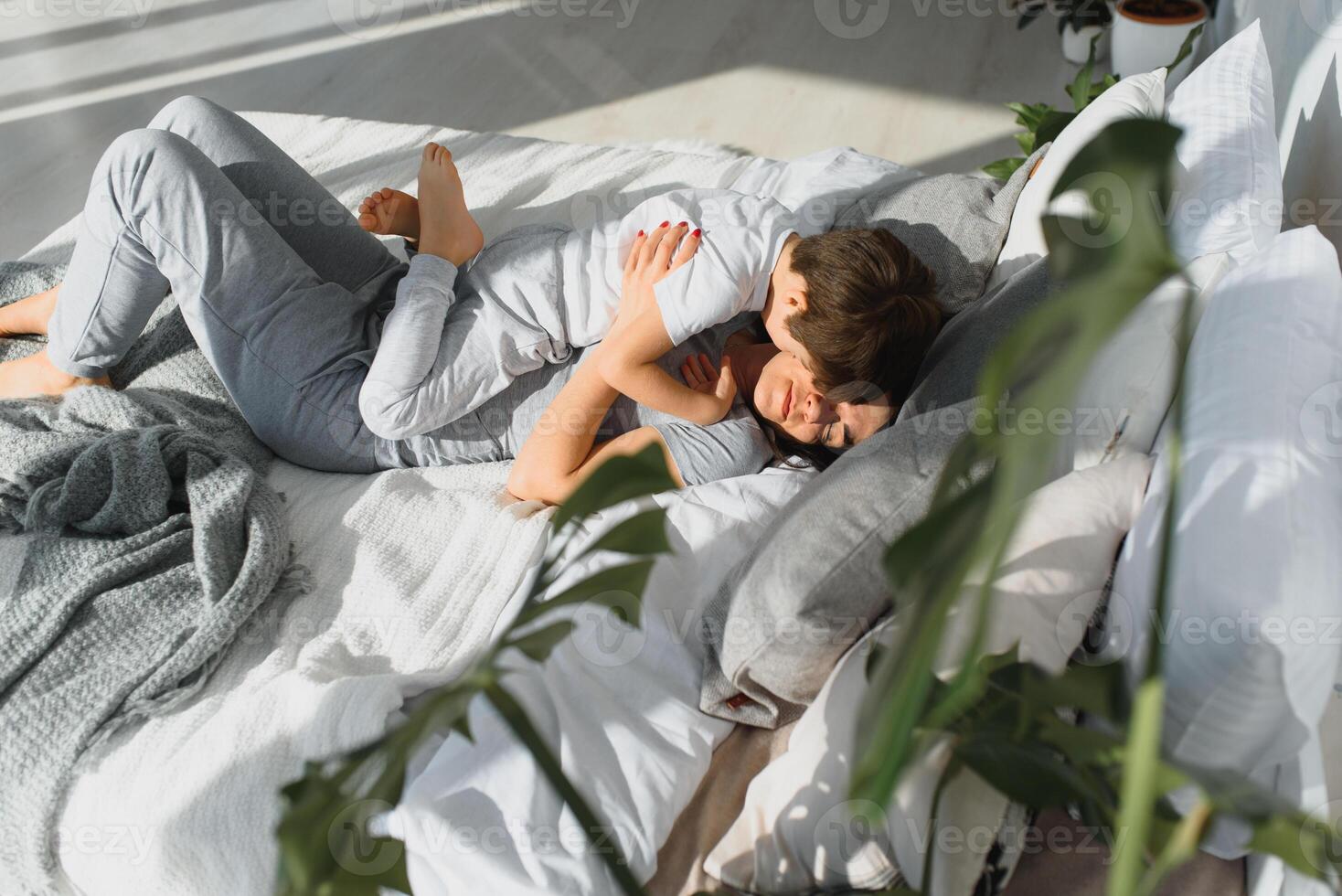 Happy Mom and son playing and laughing in their pajamas on the bed photo