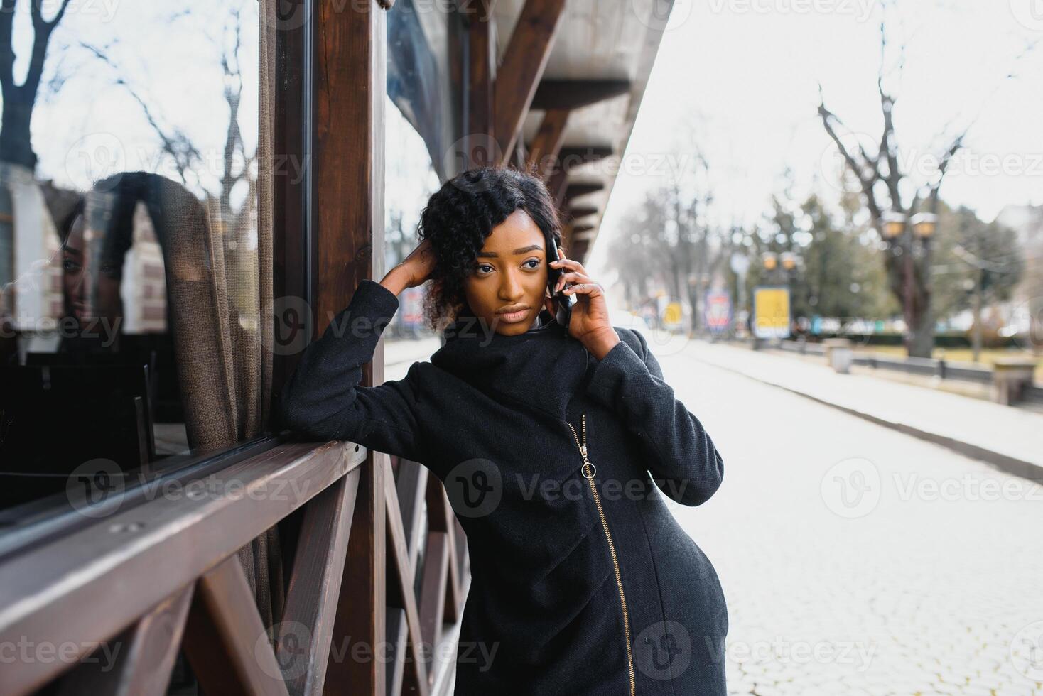 cheerful african woman using smart phone outdoors photo