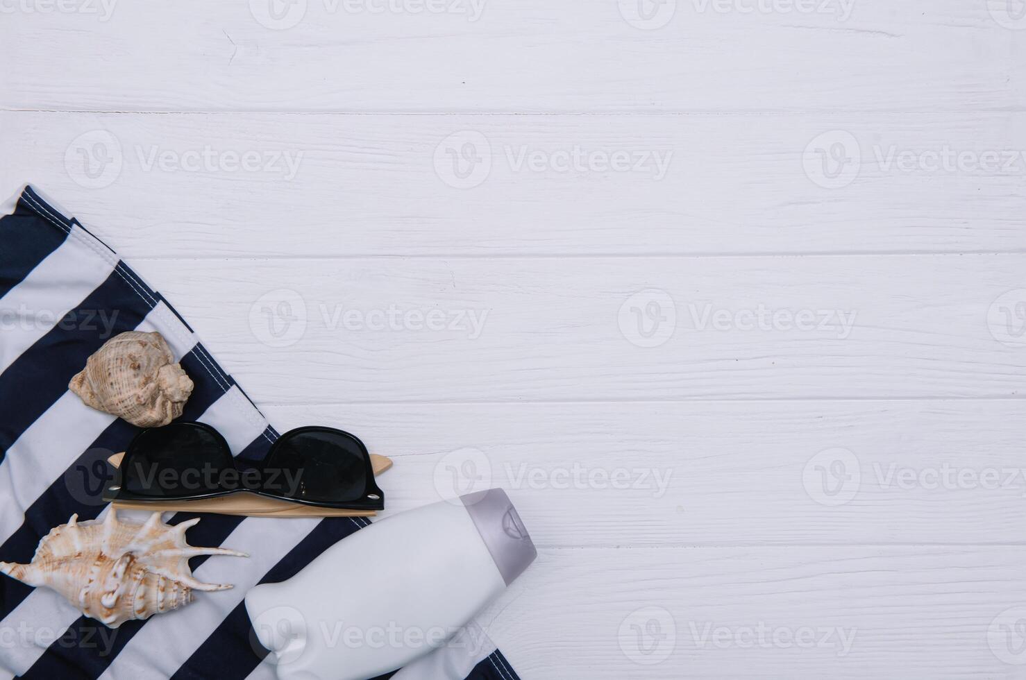 Beach accessories. Towel, flip-flops, starfish, boat and sunglasses on wooden background. Top view with copy space. Sunny toned photo