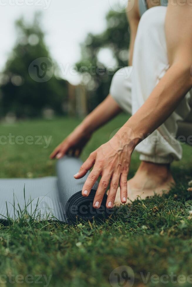 niña tendido fuera un yoga estera en el parque foto