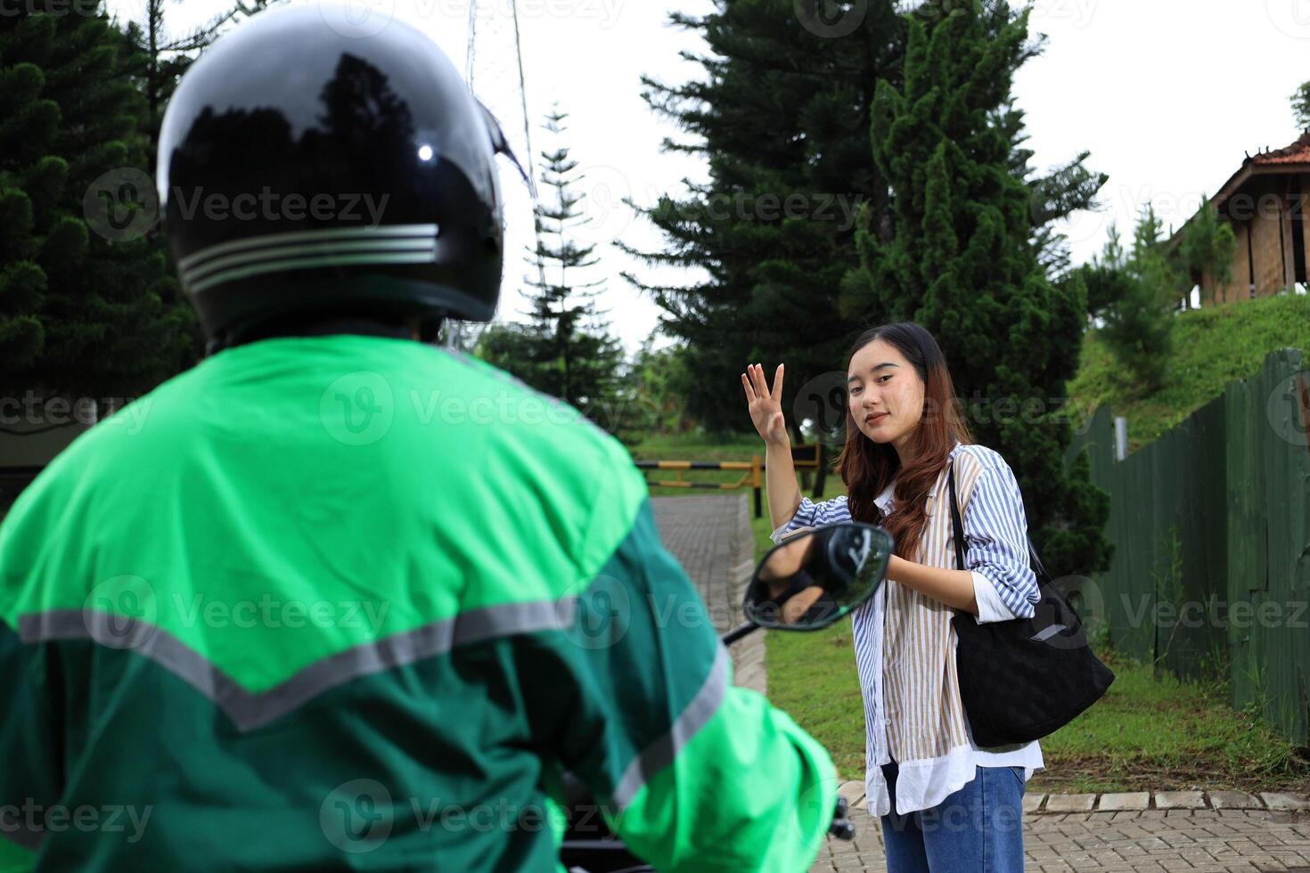 Asian Female Wave to Online Driver with Motorbike photo