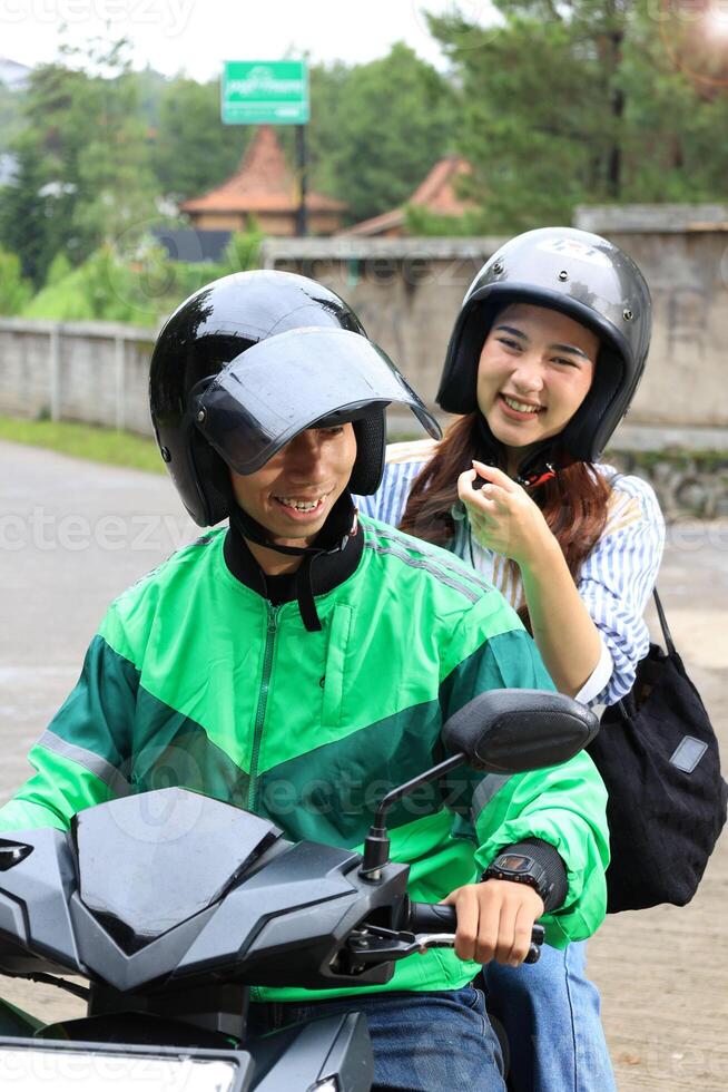 Female Passenger SMiling to the Ojek Driver Online, Showing Direction photo