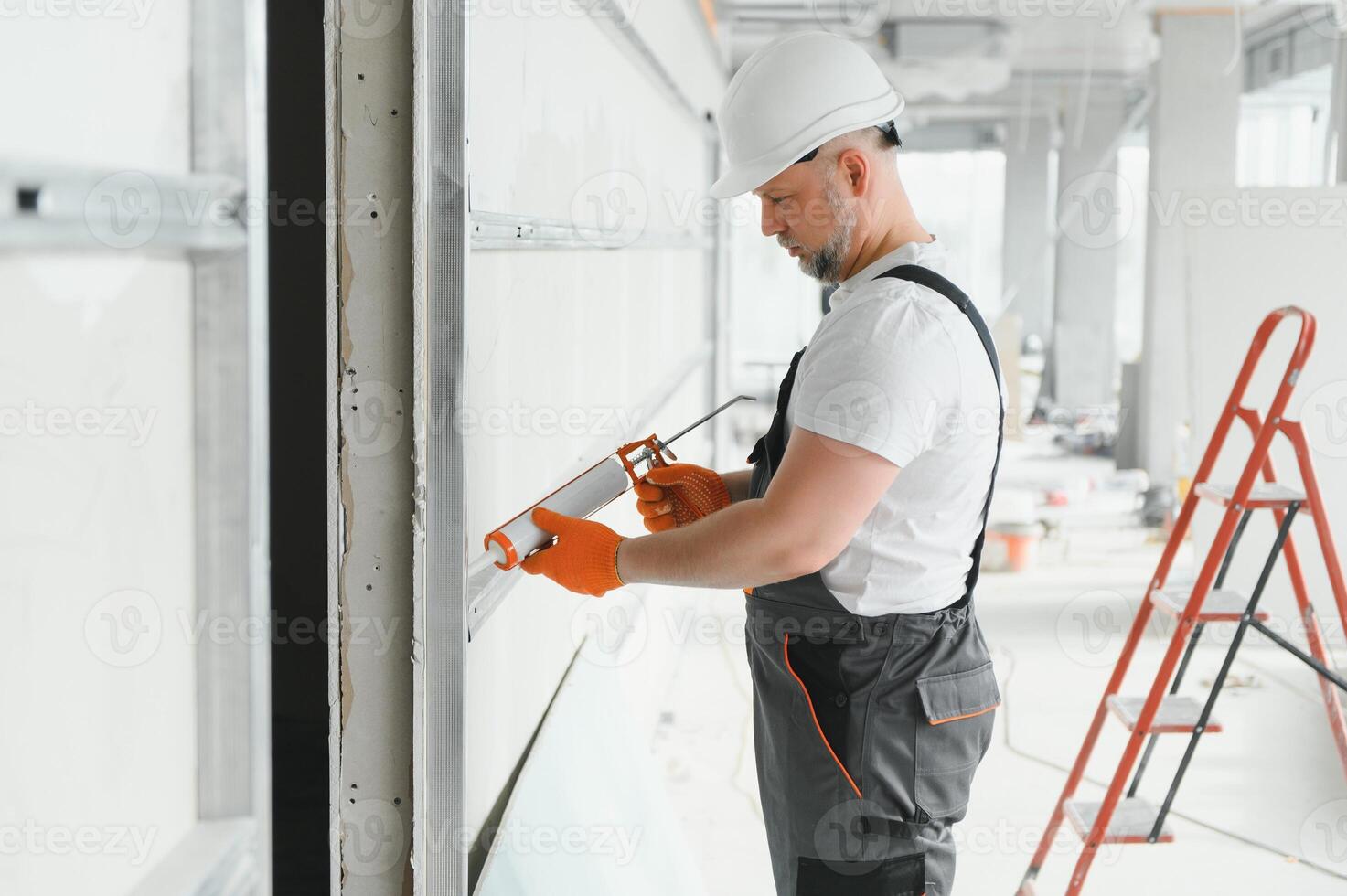 The builder fills the seam between plasterboard plates a silicone gun photo