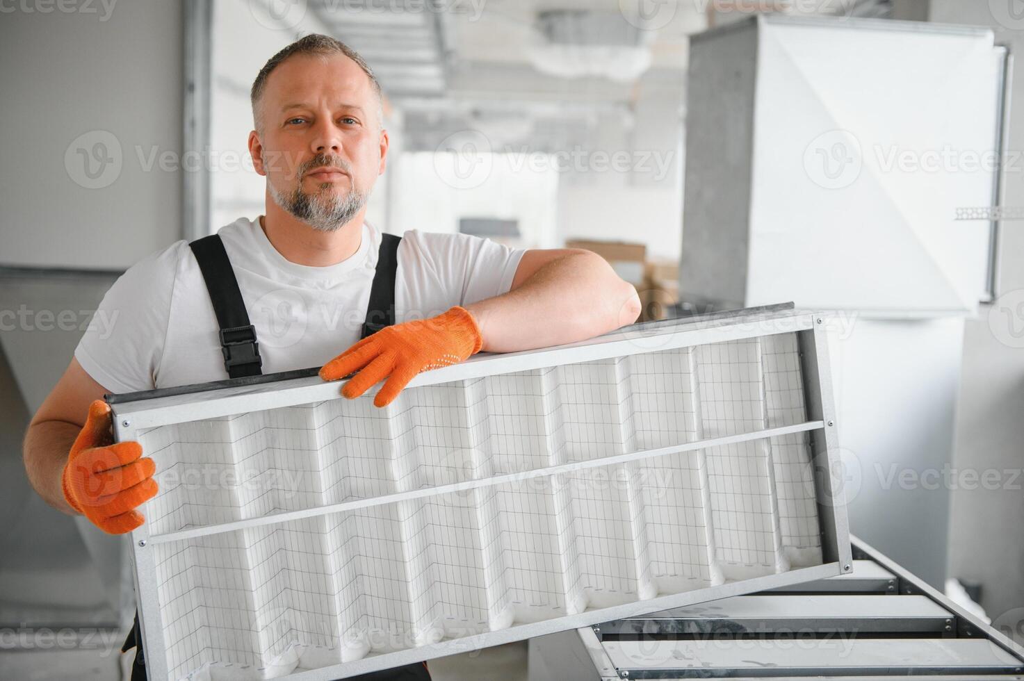 A male worker holds an air filter for air conditioning in an office space. Installation of an air conditioner. photo