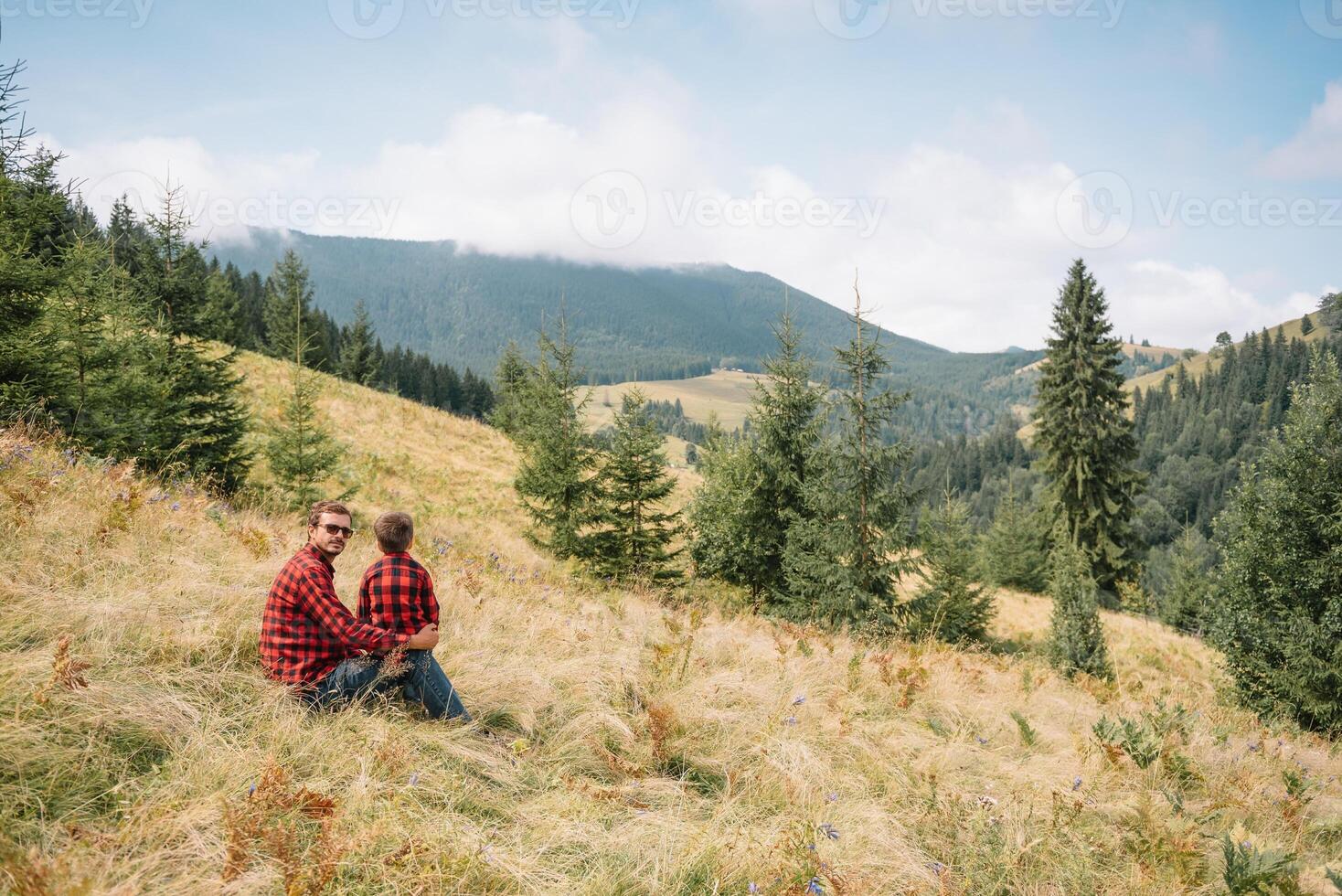 Father and child hiking in scenic mountains. Dad and son enjoying the view from the mountain top in Carpathian mountains photo