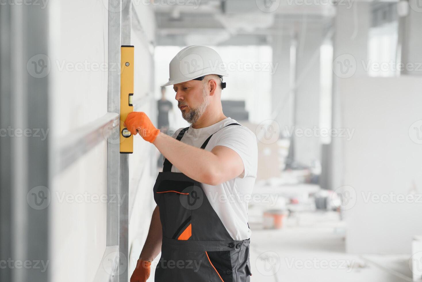 Man holding level against plasterboard, interior drywall. Attic renovation photo