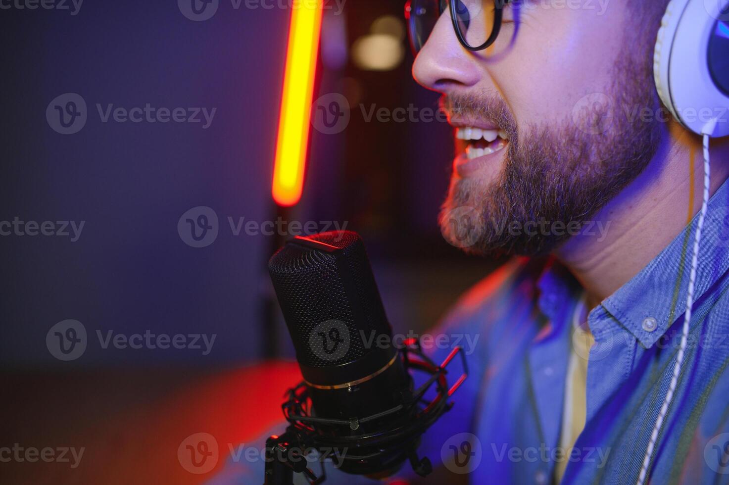Young man recording or streaming podcast using microphone at his small broadcast studio. Content creator. photo