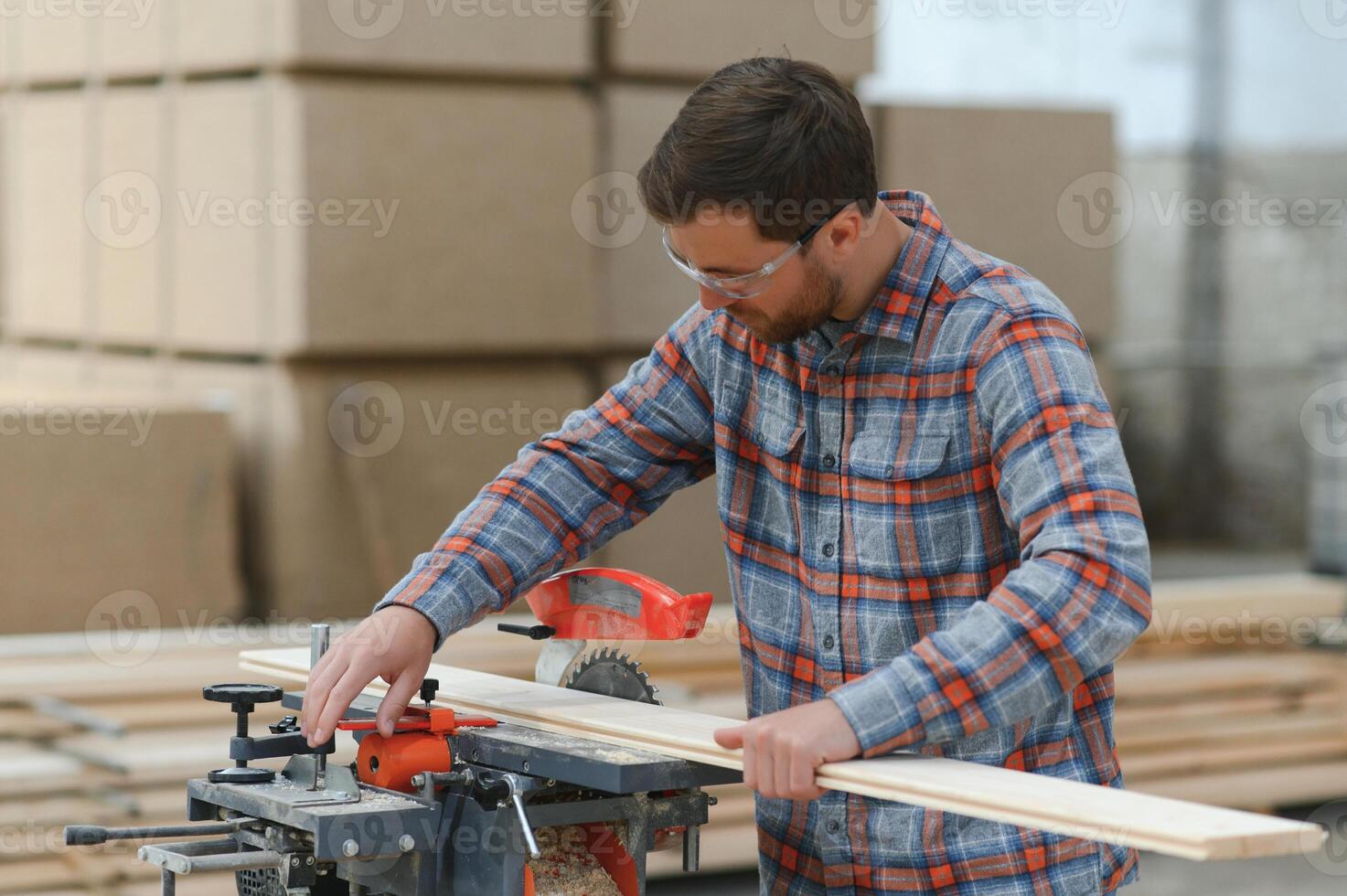 Wood cutting table with electric circular saw. Professional carpenter in uniform cutting wooden board at sawmill carpentry manufacturing . Sawing machine photo