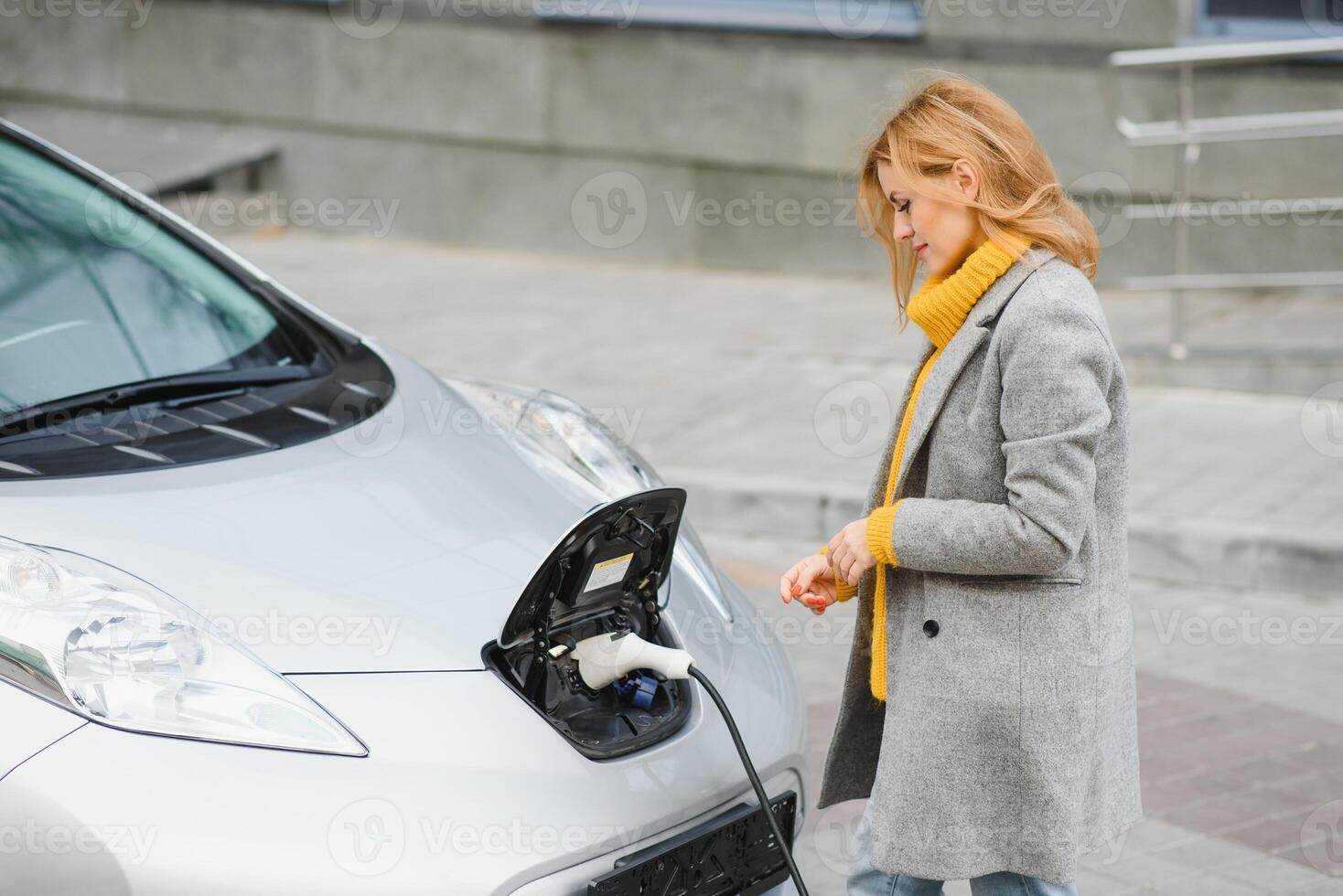 Woman charging electro car at the electric gas station. photo