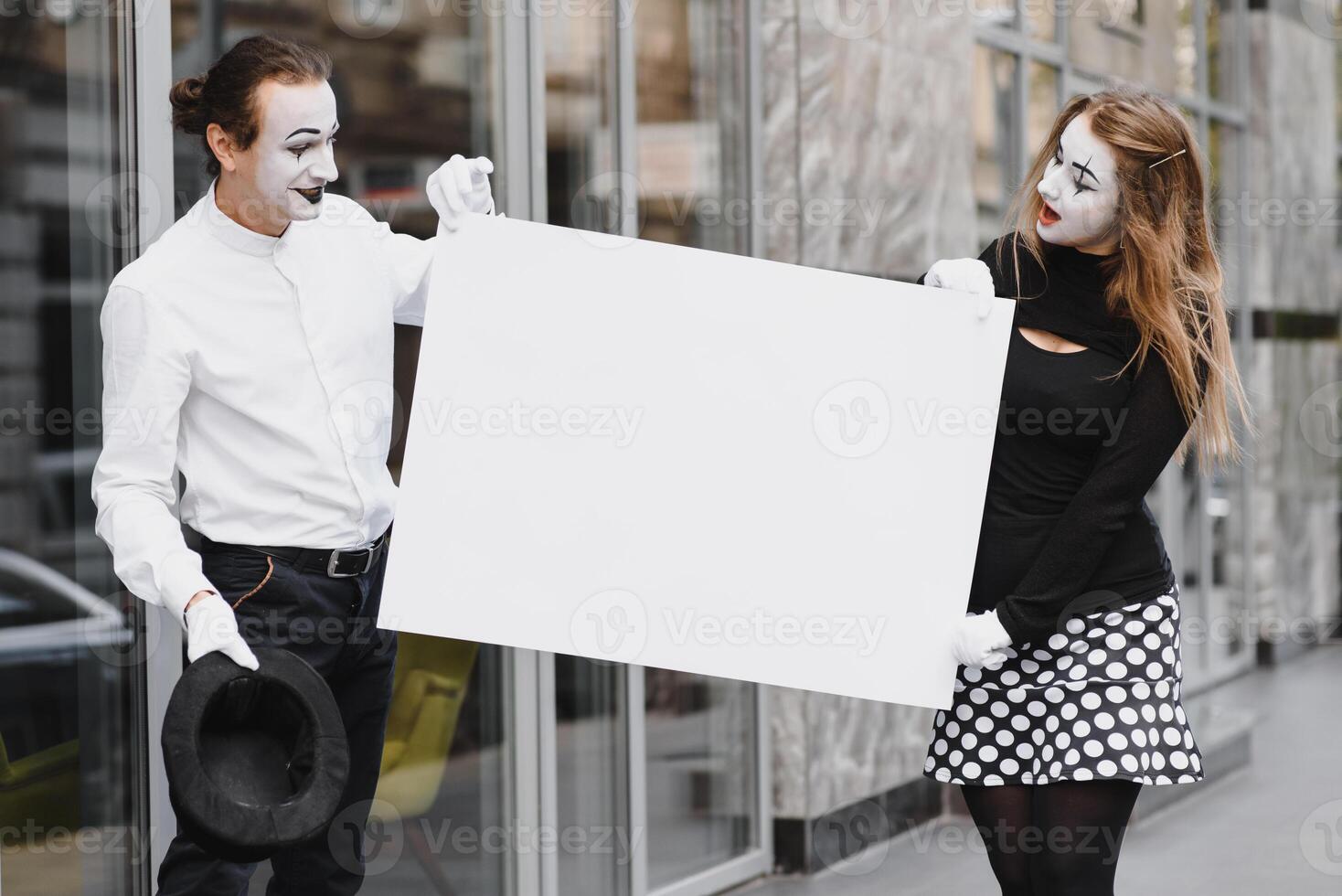 Your text here. Actors mimes holding empty white letter. Colorful portrait with gray background. April fools day photo