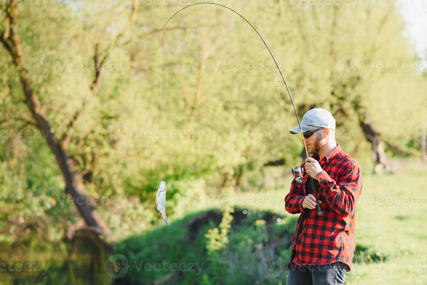 Fisher man fishing with spinning rod on a river bank, spin fishing, prey fishing photo