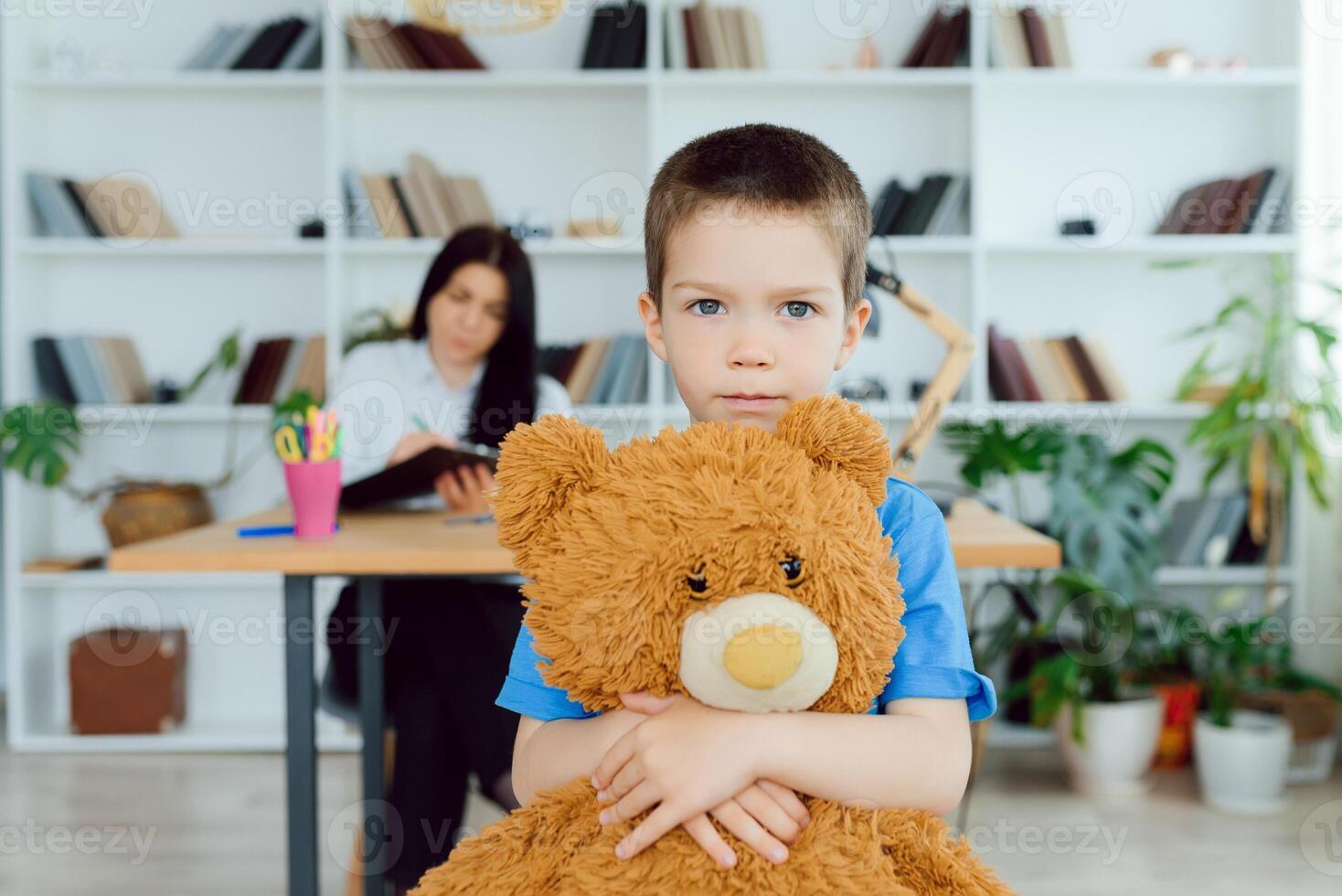 Young female psychologist working with little boy in office photo