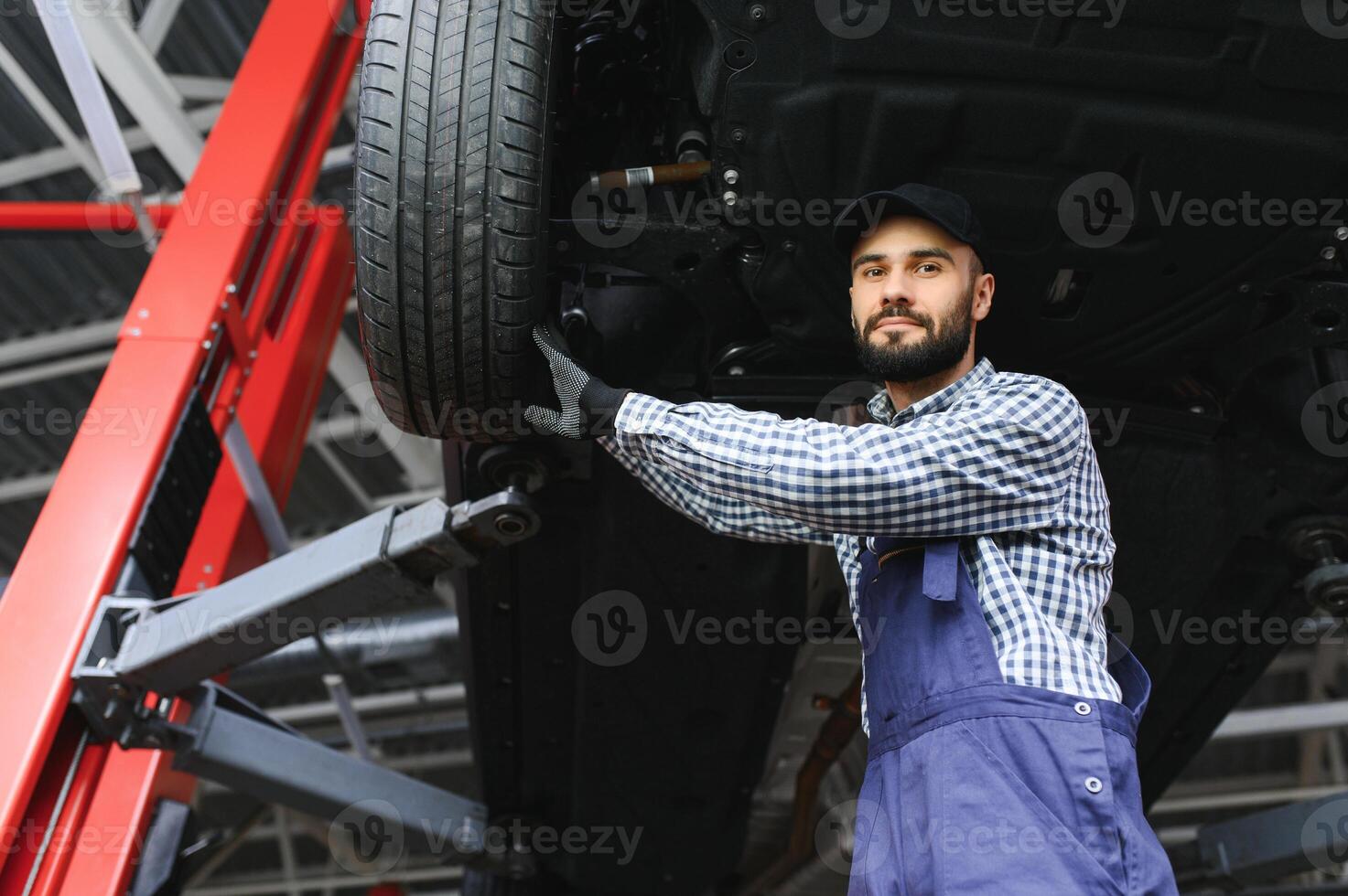 Auto mechanic working underneath a lifted car photo