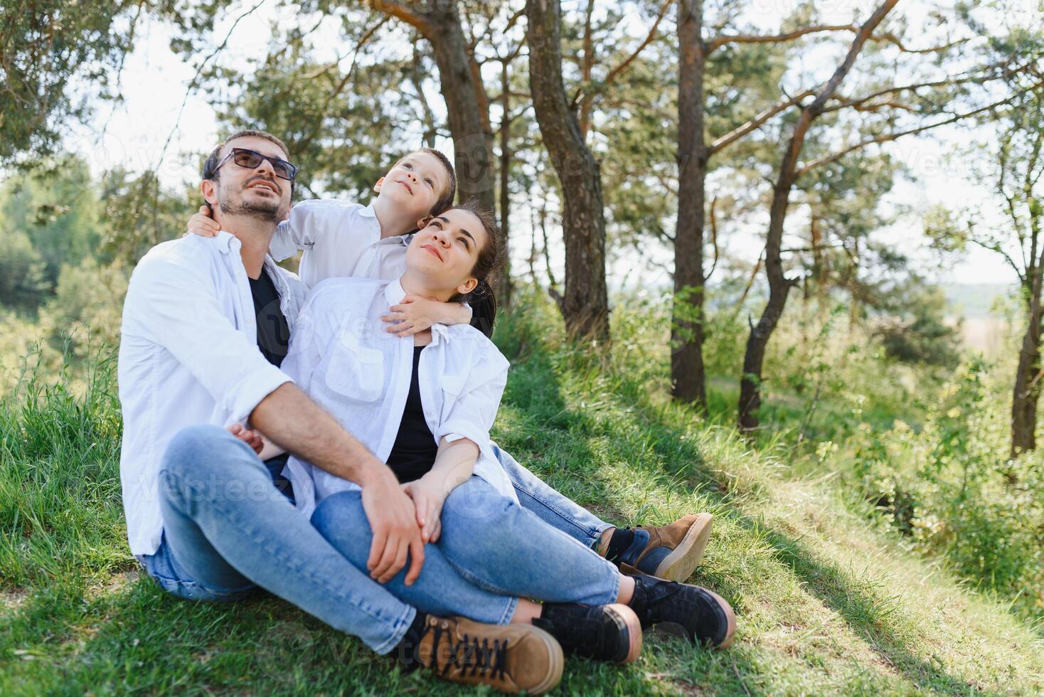 happy young family spending time outdoor on a summer day have fun at beautiful park in nature while sitting on the green grass. Happy family. photo