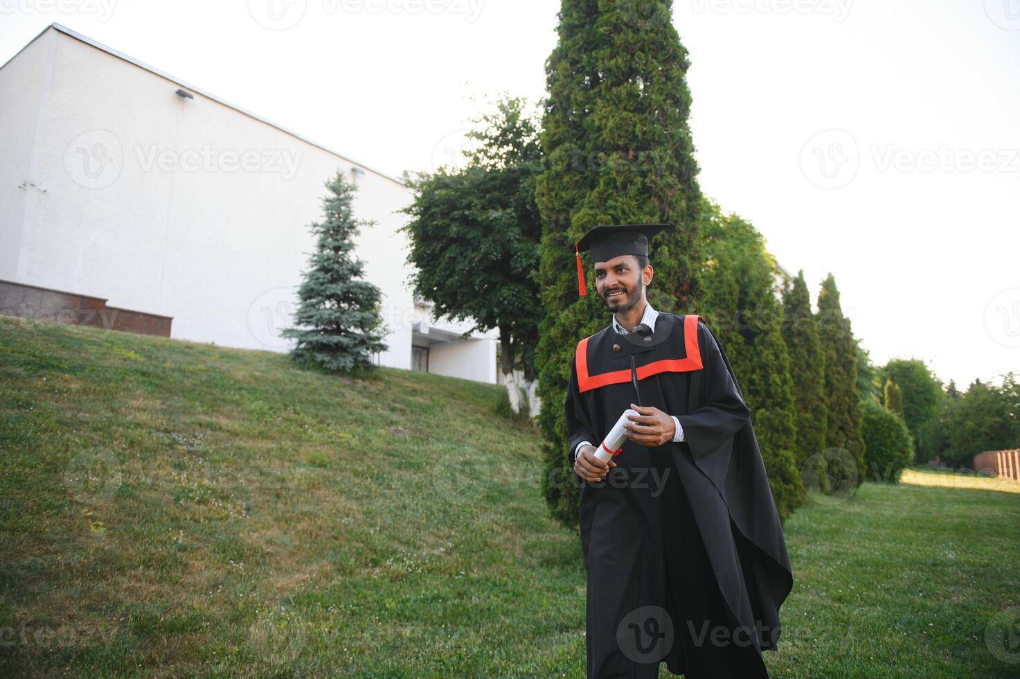 Portrait of indian handsome male graduate in graduation robe. photo