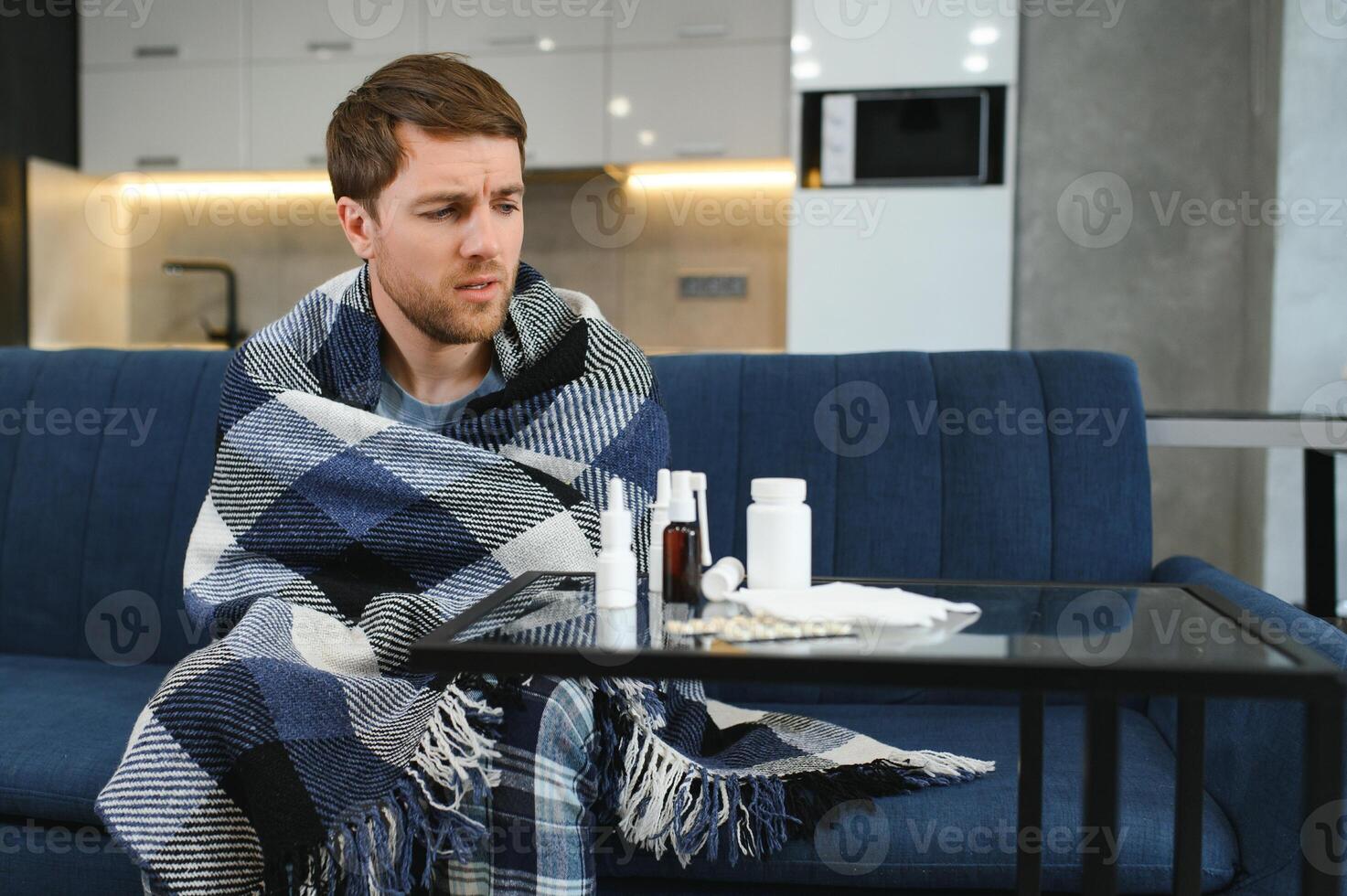 Man wrapped in plaid on the sofa feeling sick illness at home photo