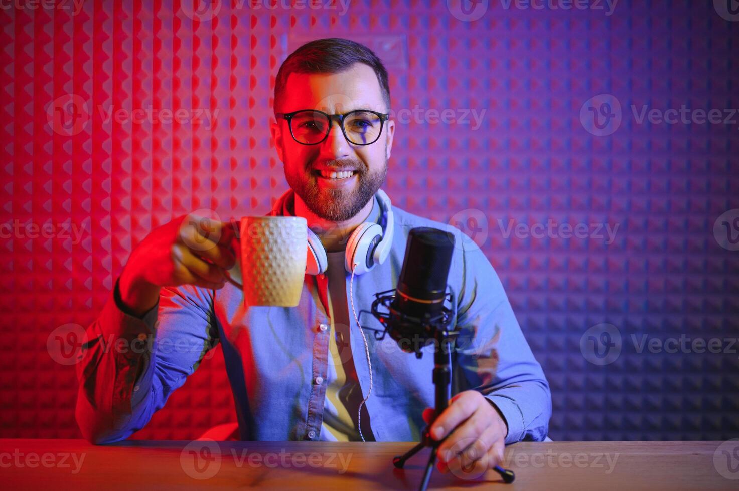 Young man recording or streaming podcast using microphone at his small broadcast studio. Content creator. photo