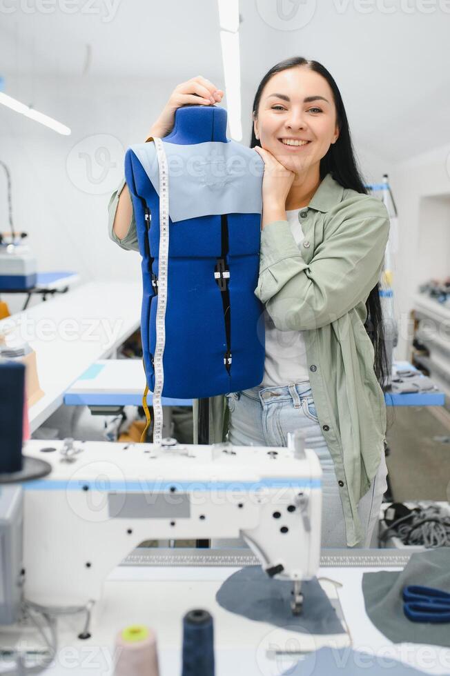 positivo joven mujer de coser con profesional máquina a taller. foto