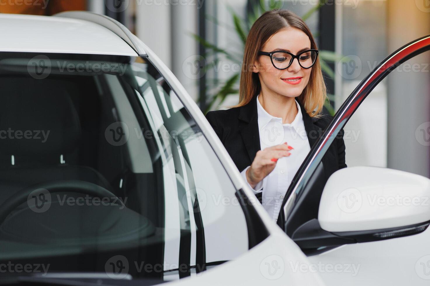 auto business, car sale, consumerism and people concept - happy woman taking car key from dealer in auto show or salon. photo