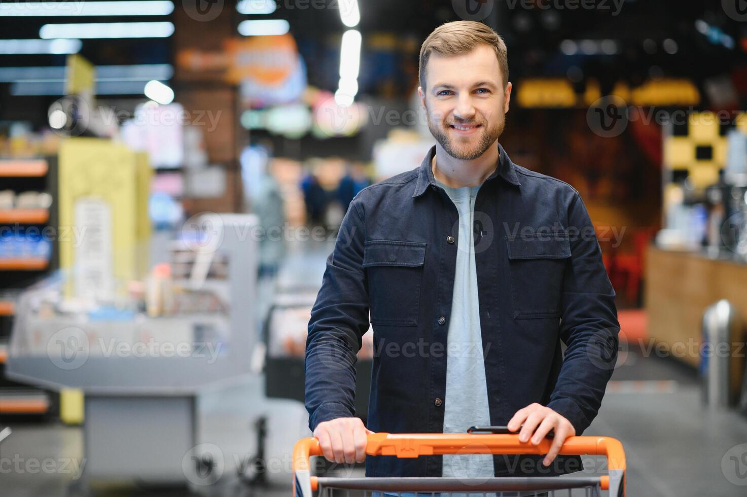 joven hombre comprando comestibles a el supermercado. otro clientes en antecedentes. consumismo concepto. foto
