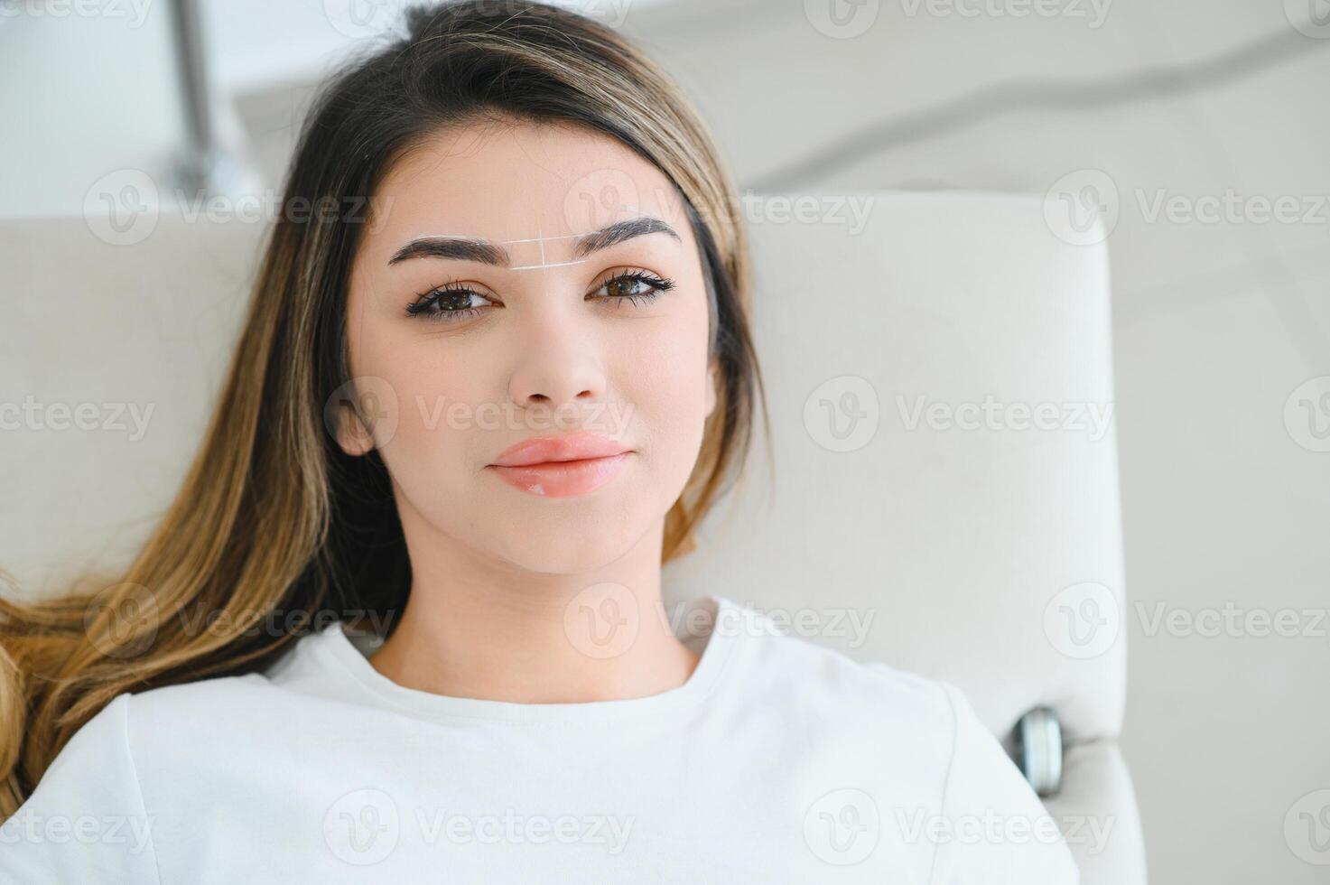 Young woman during professional eyebrow mapping procedure. photo