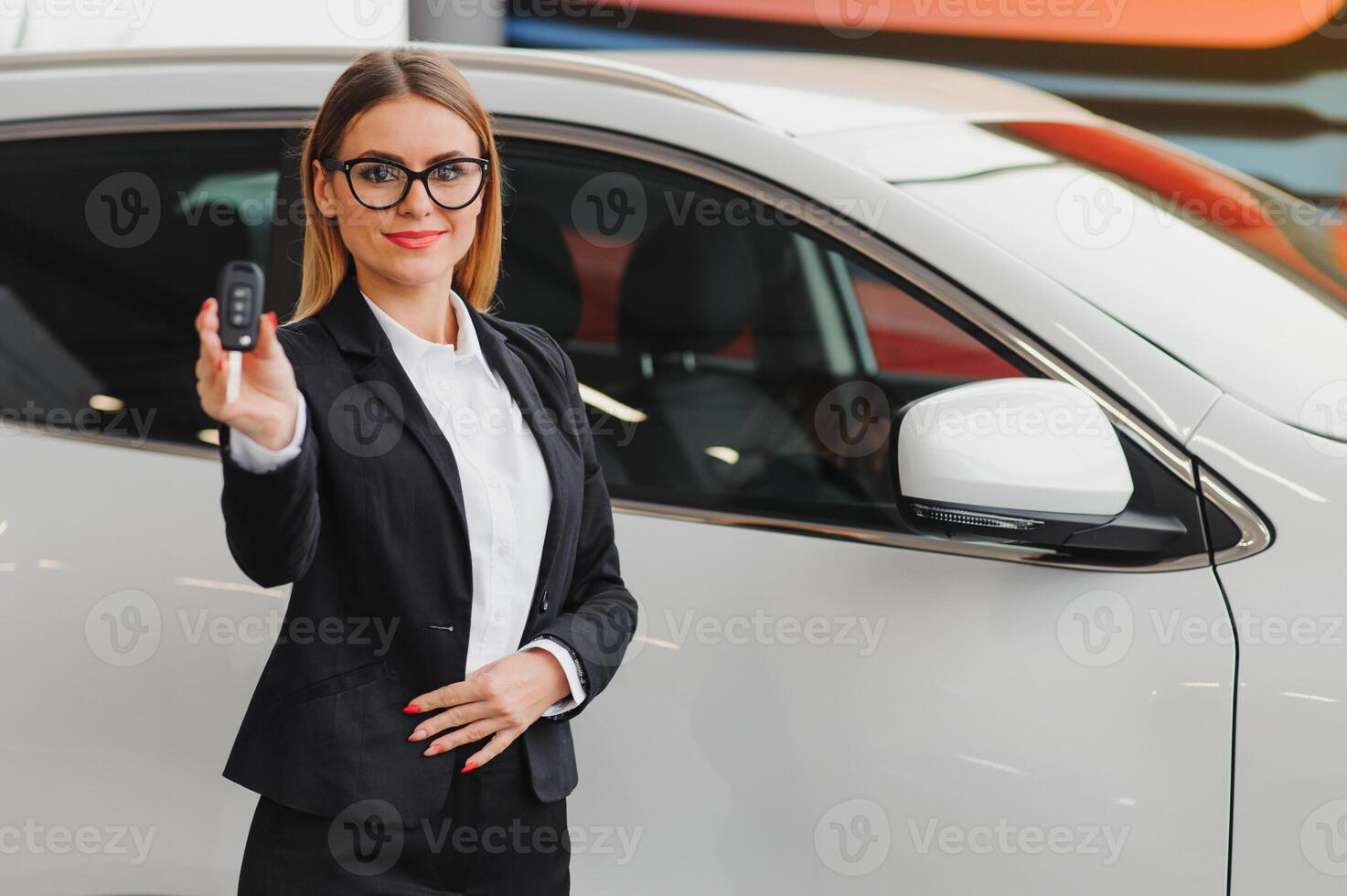 auto business, car sale, consumerism and people concept - happy woman taking car key from dealer in auto show or salon. photo