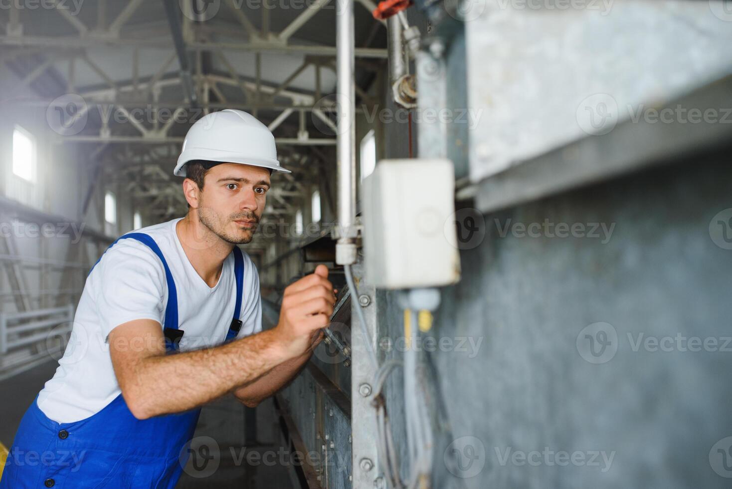 un joven hermoso empleado de un moderno fábrica en un blanco duro. en el antecedentes es un grande tienda para el producción. foto